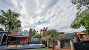 A residential area with a swimming pool, a brick house, and a stone house. - Residencial Los Lapachos (Puerto Iguazú)