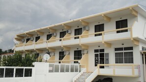 A multi-story building with balconies, air conditioning units, and a staircase leading to the entrance. - Hotel Anagros (Rhodes)