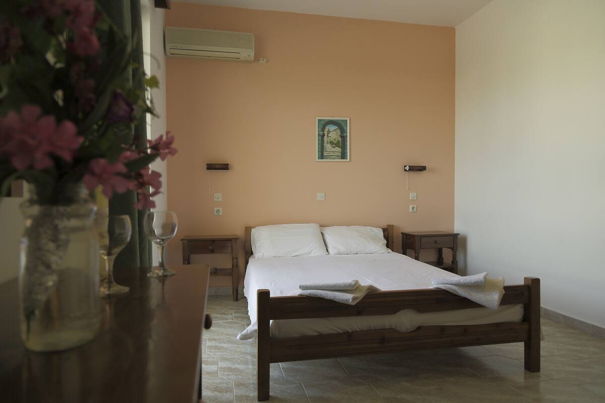 Un dormitorio con una cama de madera, una mesita de noche y un jarrón con flores.