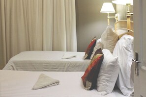 Una habitación de hotel con dos camas, una lámpara y una cortina.