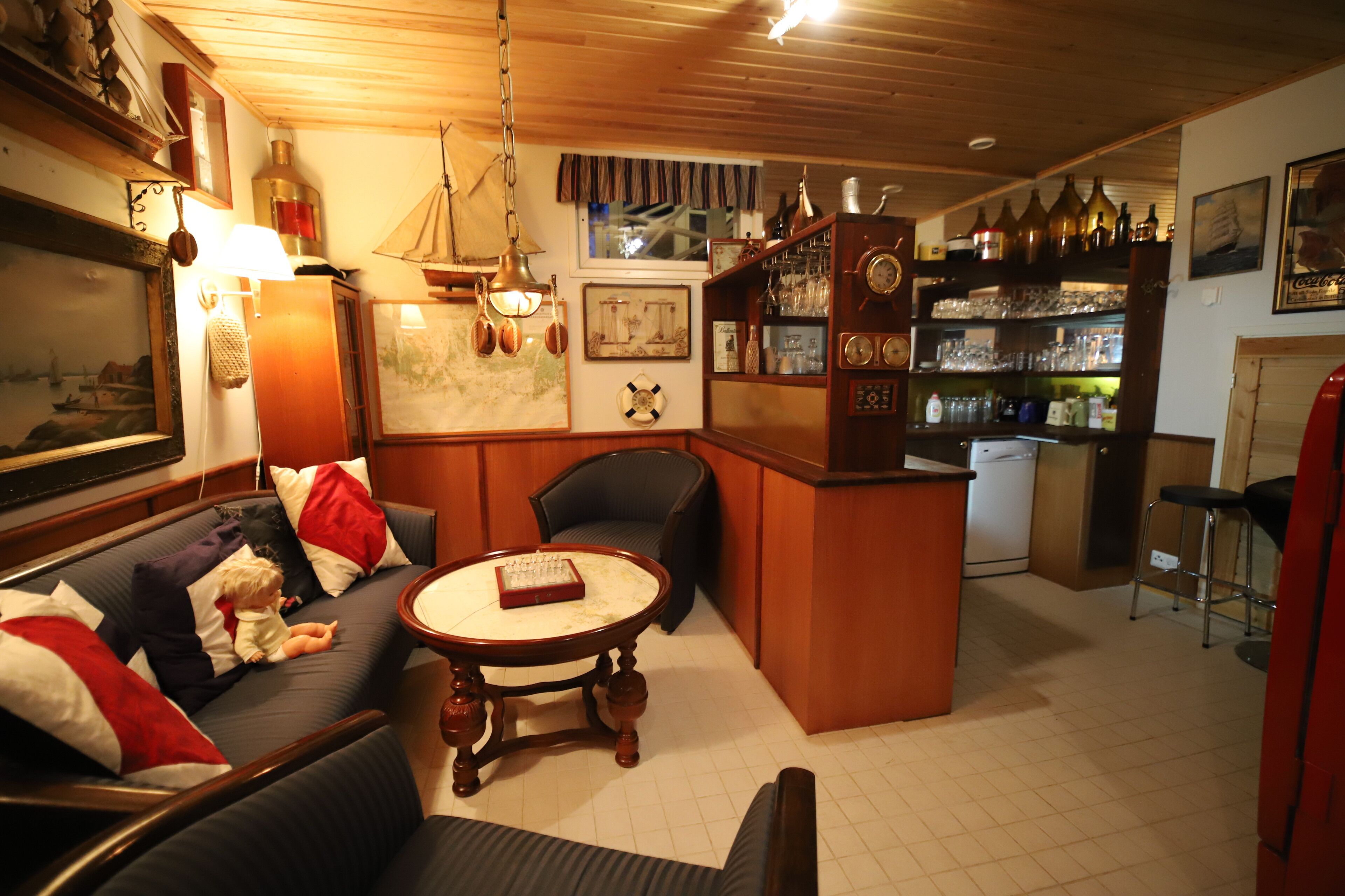 A cozy bar area with a wooden bar counter, a seating area with a round table, and a refrigerator.