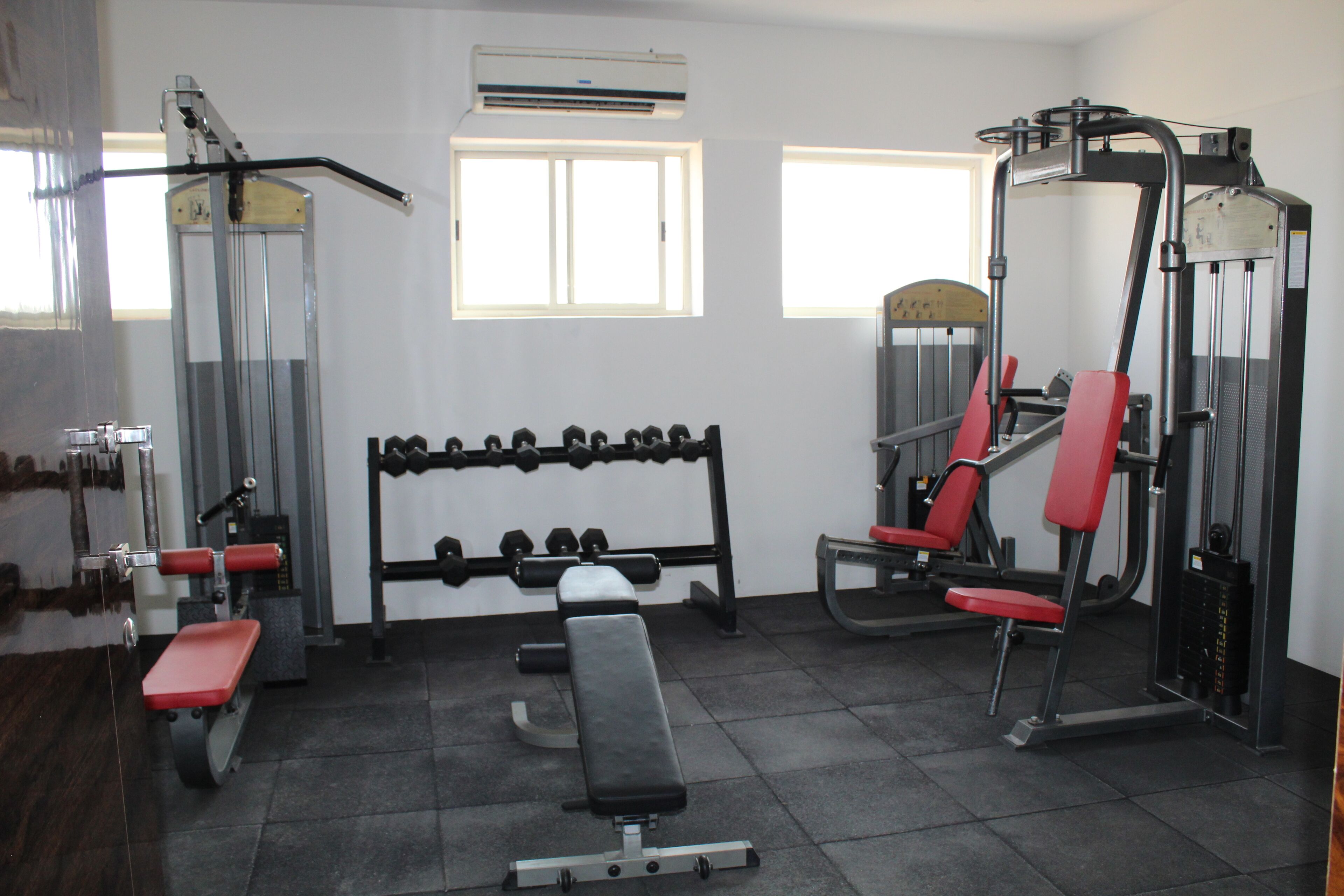 A gym with various exercise equipment, including dumbbells, a bench, and weight machines.