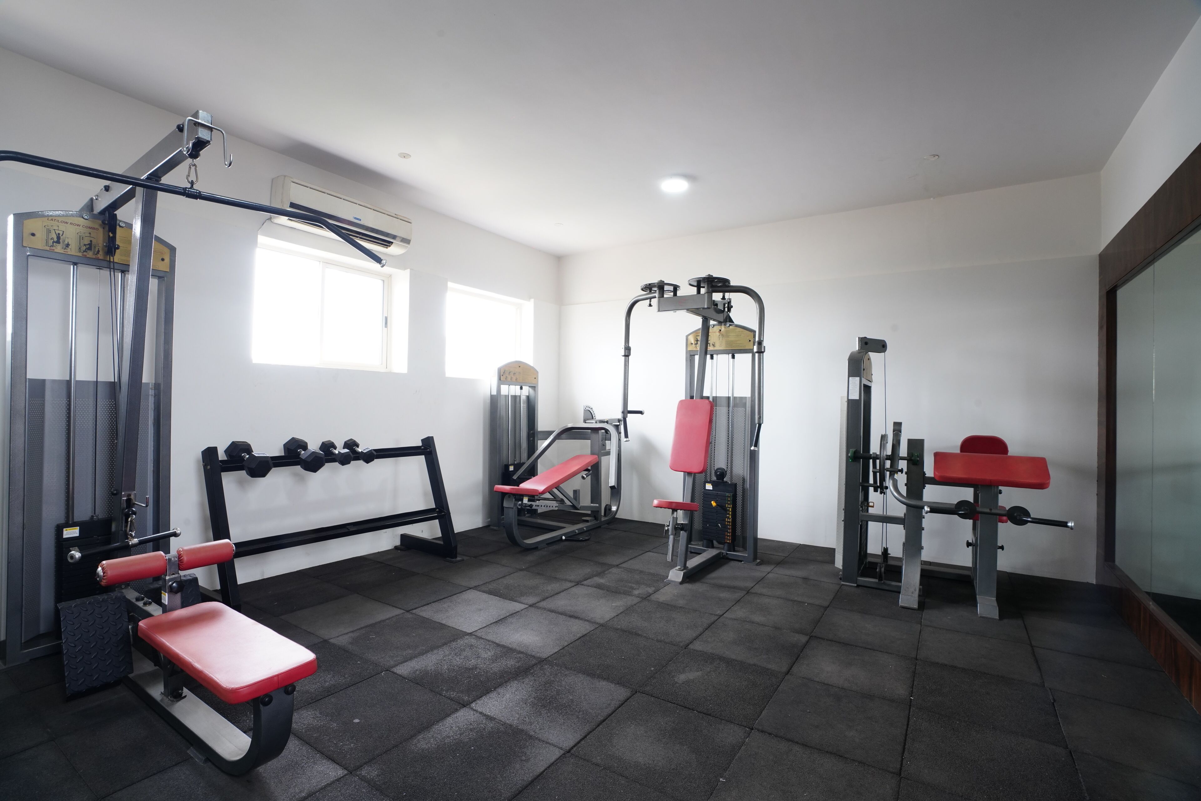 Ein Fitnessstudio mit verschiedenen Trainingsgeräten, darunter Bänke und Kraftgeräte.