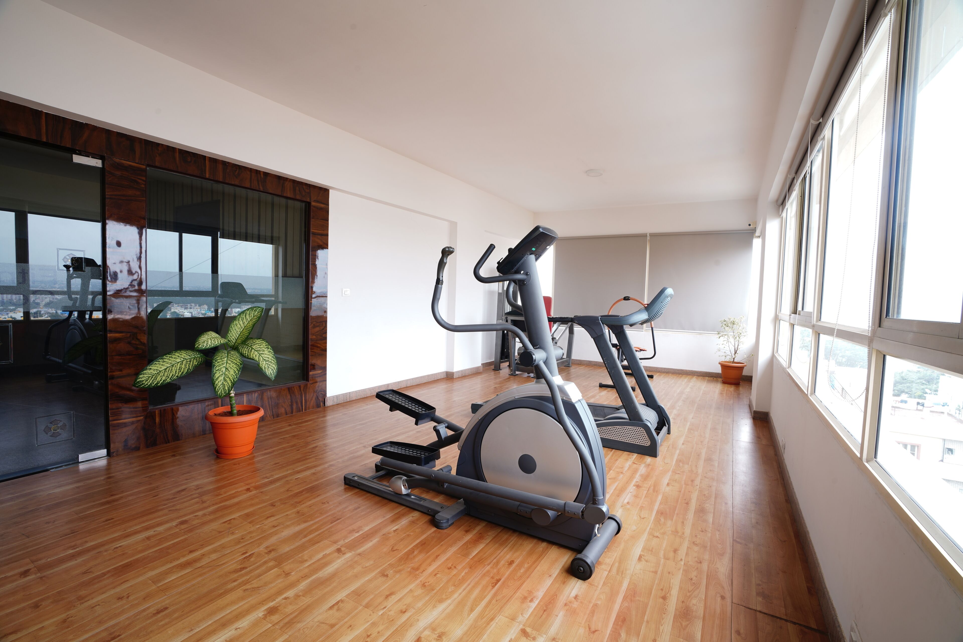 Amplia habitación con piso de madera, un ventanal grande y equipo de ejercicio que incluye una bicicleta estática y una elíptica.