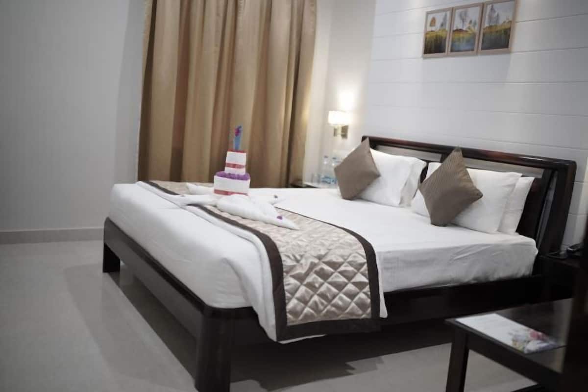 A hotel room with a bed, a nightstand, a lamp, and a wall-mounted picture.