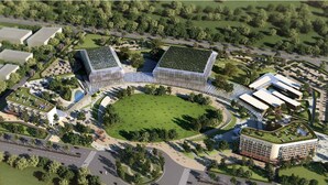 Eine Vogelperspektive eines modernen Gebäudekomplexes mit mehreren Strukturen, einem zentralen Grünbereich und umliegenden Grünflächen.