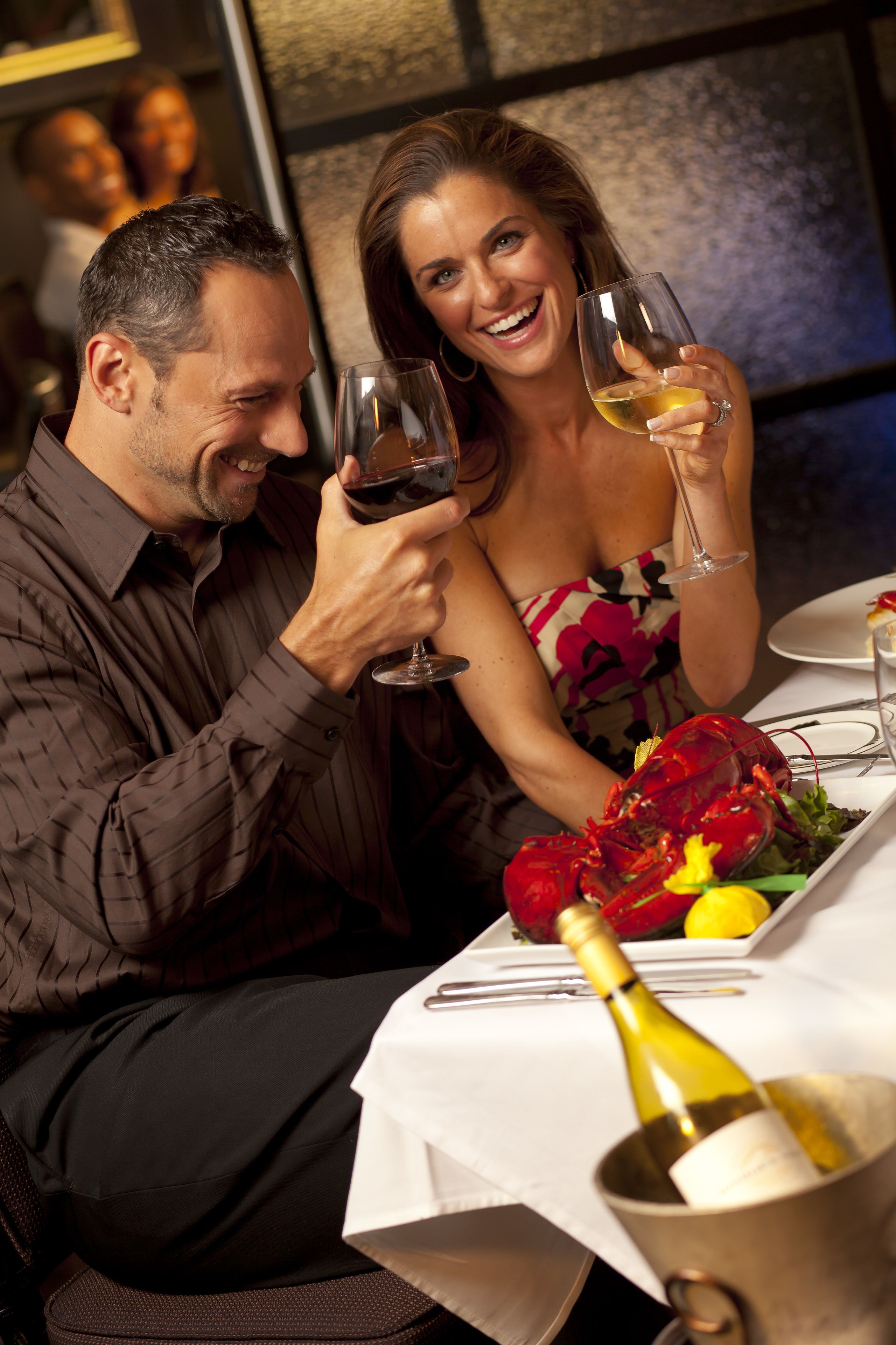 Una mesa de comedor con una langosta, copas de vino y una botella de vino.