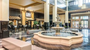 A spacious lobby with a central fountain, seating areas, and signs for LBV Steakhouse and Pasta. - Mountaineer Casino Resort (New Cumberland)