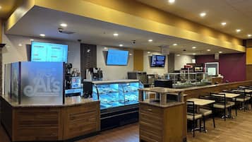 A modern coffee shop with a counter, digital menu boards, and seating area.