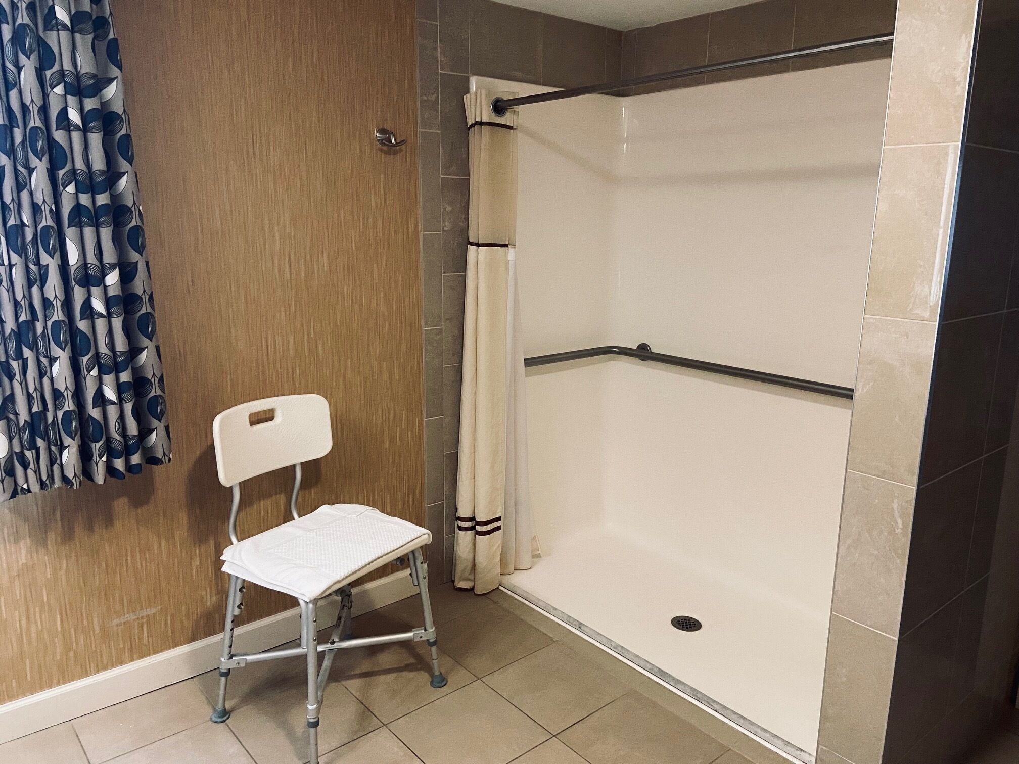 Ein barrierefreies Duschareal mit Holzwand, Fliesenboden und Duschvorhang.