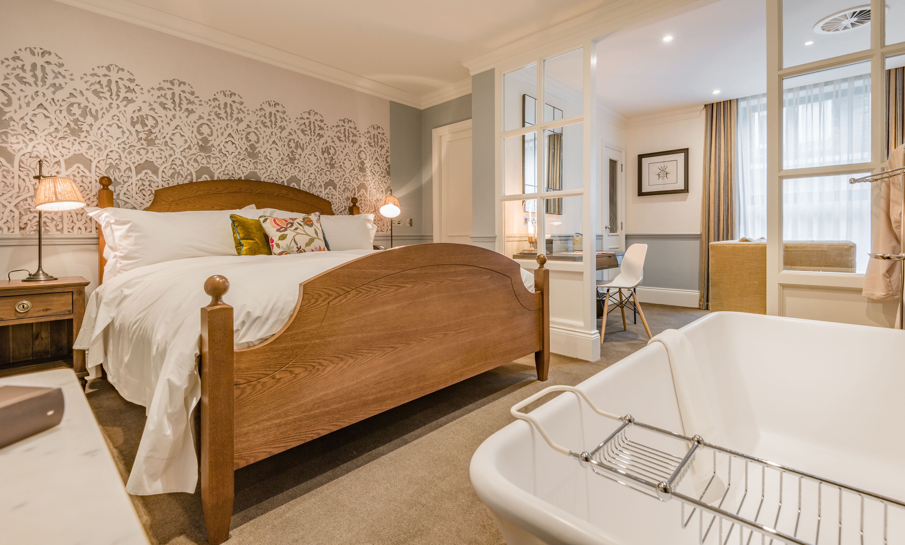 Une chambre à coucher avec un lit en bois, une baignoire blanche et un bureau avec une chaise.