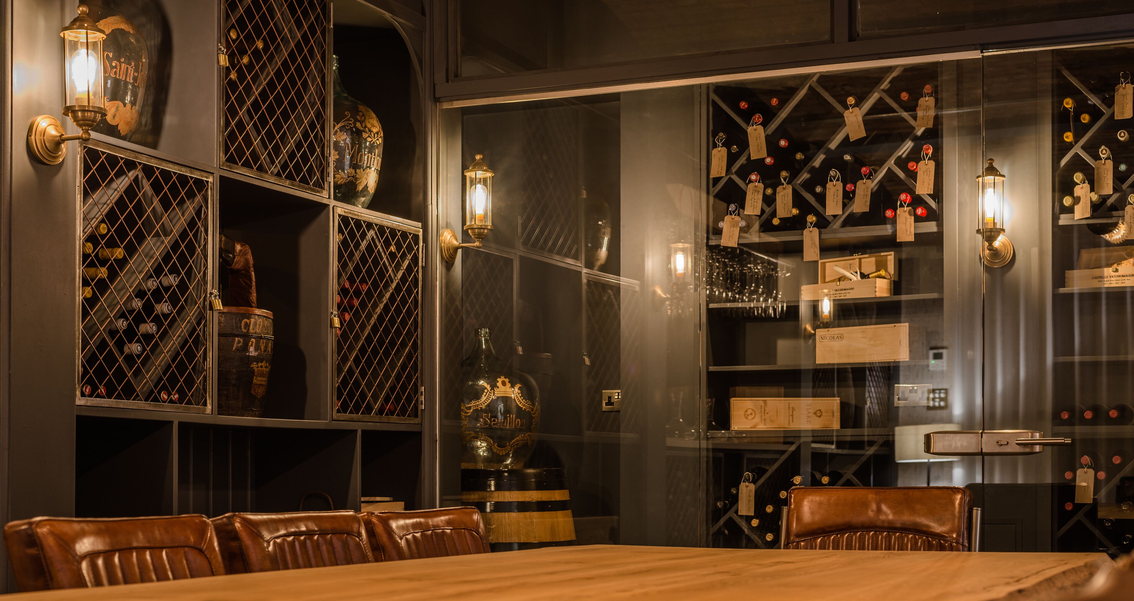 Un espace repas avec une table en bois et des chaises en cuir, entouré de vitrines contenant des bouteilles et des boîtes.