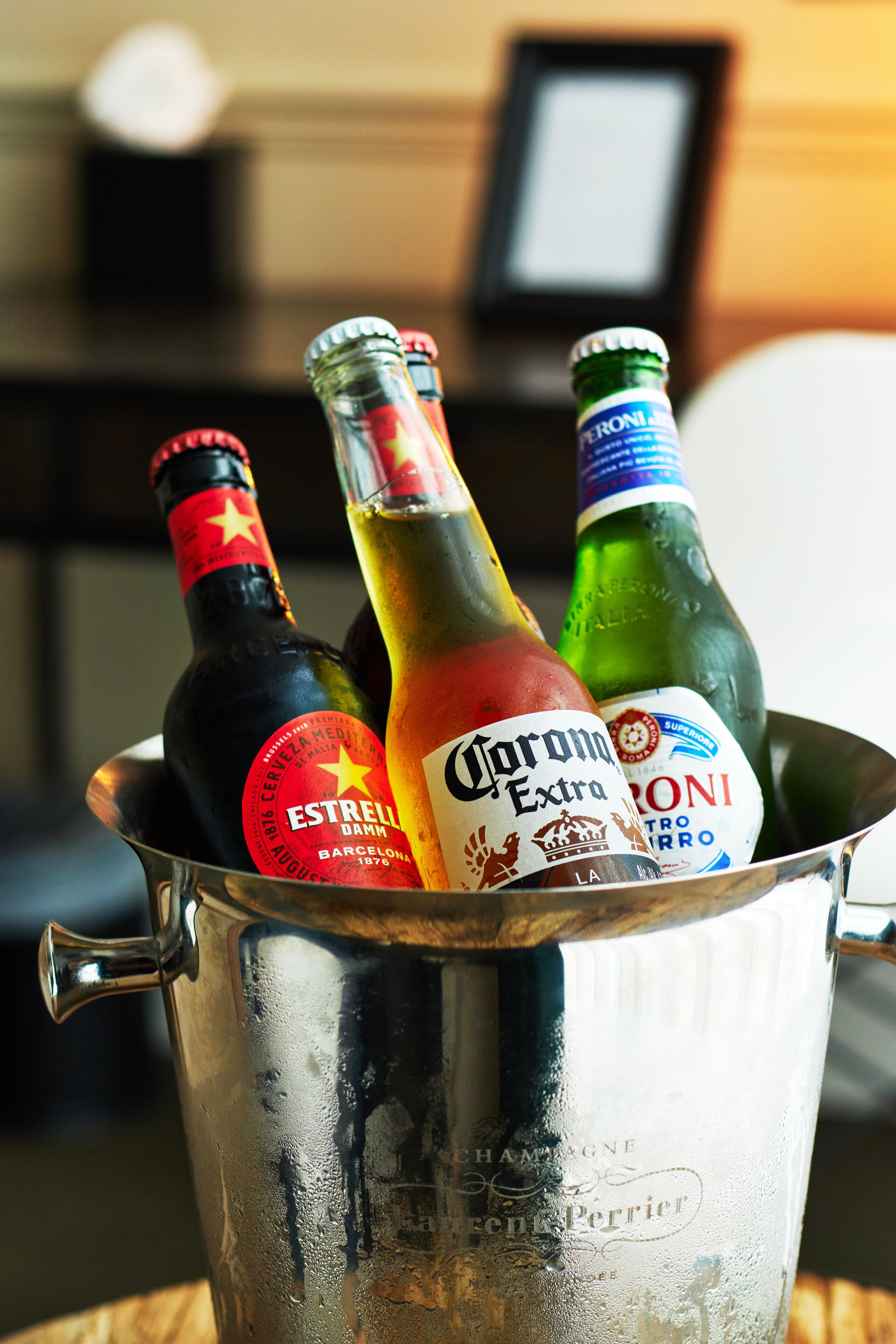 Un balde de metal con botellas de Estrella, Corona y otras bebidas alcohólicas.