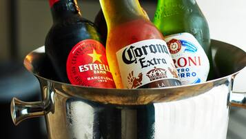 Un balde de metal con botellas de Estrella, Corona y otras bebidas alcohólicas.