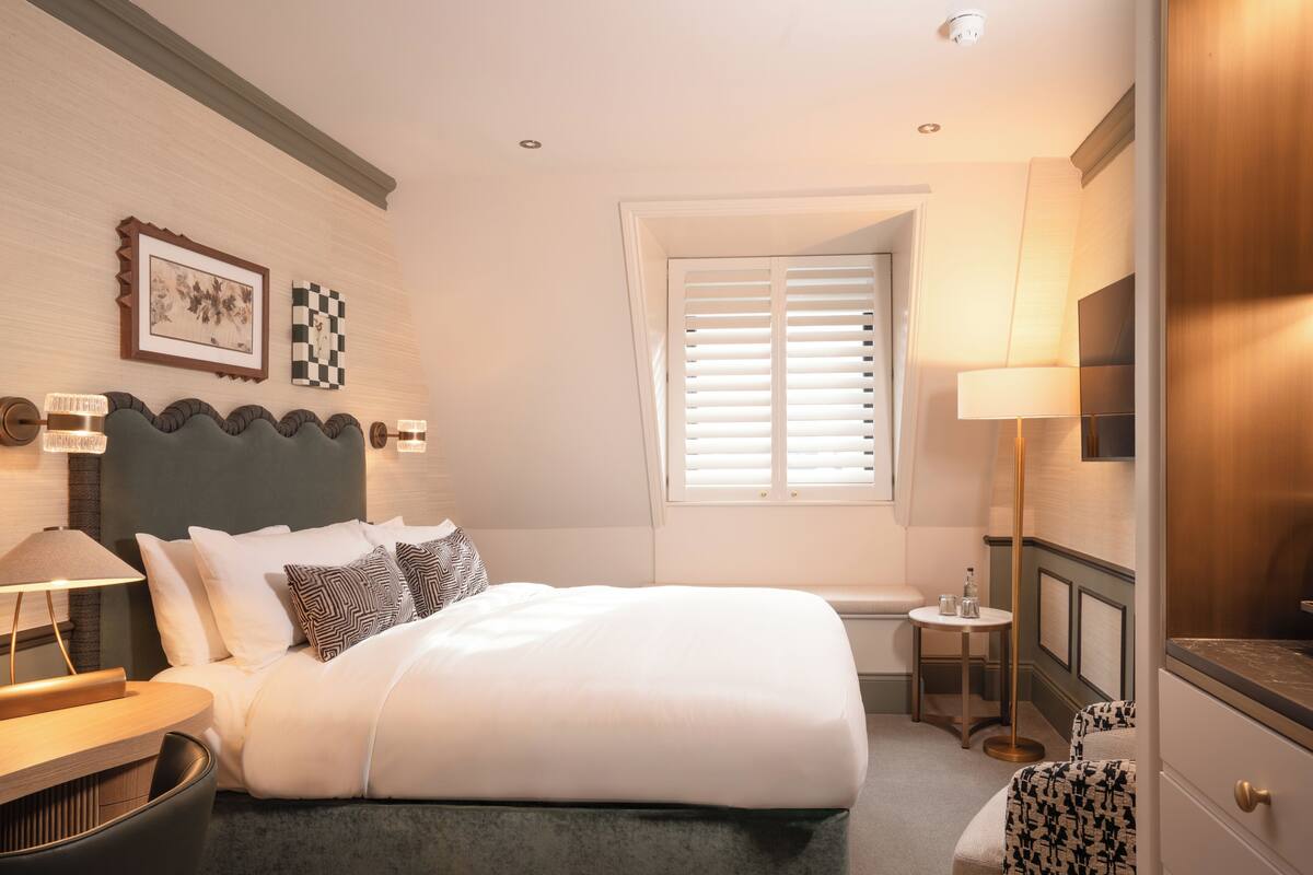 A neatly arranged bedroom with a bed, bedside table, lamp, and a small table with a lamp.