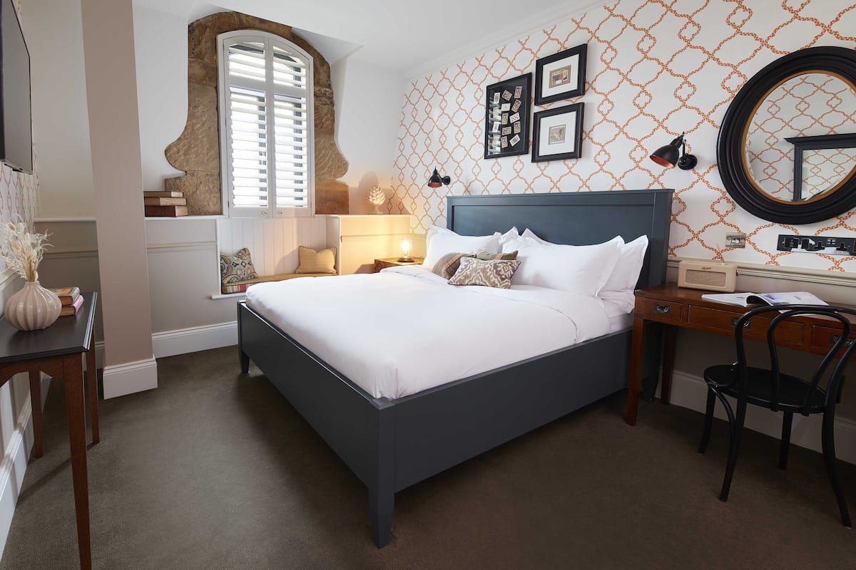 A bedroom with a bed, bedside tables, a desk, and a chair.