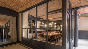 A dining area with a brick ceiling, large windows, and a view of the kitchen. - King Street Townhouse (Manchester)