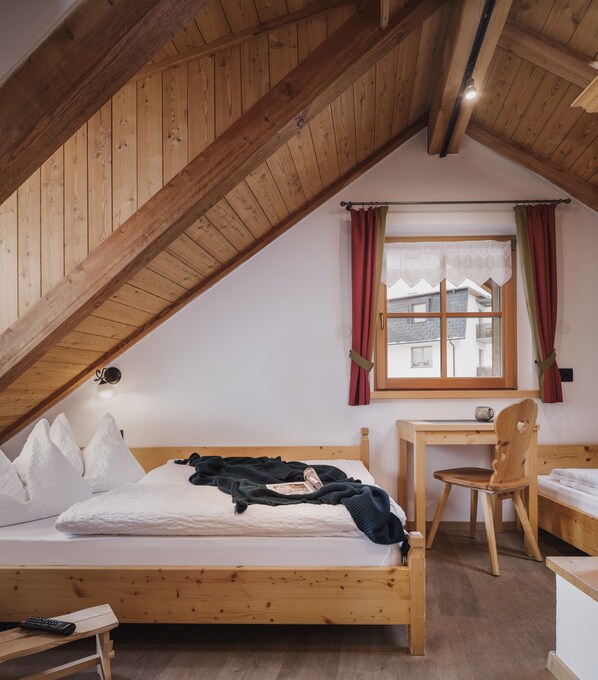 A bedroom with a sloped ceiling, a bed, a desk, and a chair. - Chalet Tyrolian Apartments - by Familiaris - Pools 500 meters (Valdaora)