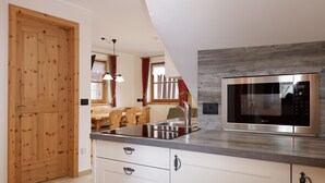 A modern kitchen with a stainless steel microwave, wooden cabinets, and a built-in sink. - Chalet Tyrolian Apartments - by Familiaris - Pools 500 meters (Valdaora)