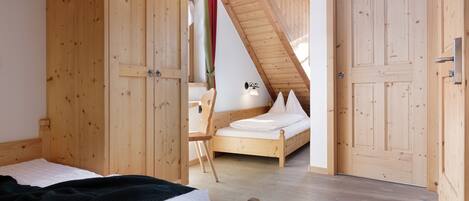 Una camera da letto con pareti in legno, un soffitto spiovente e un letto con biancheria bianca.