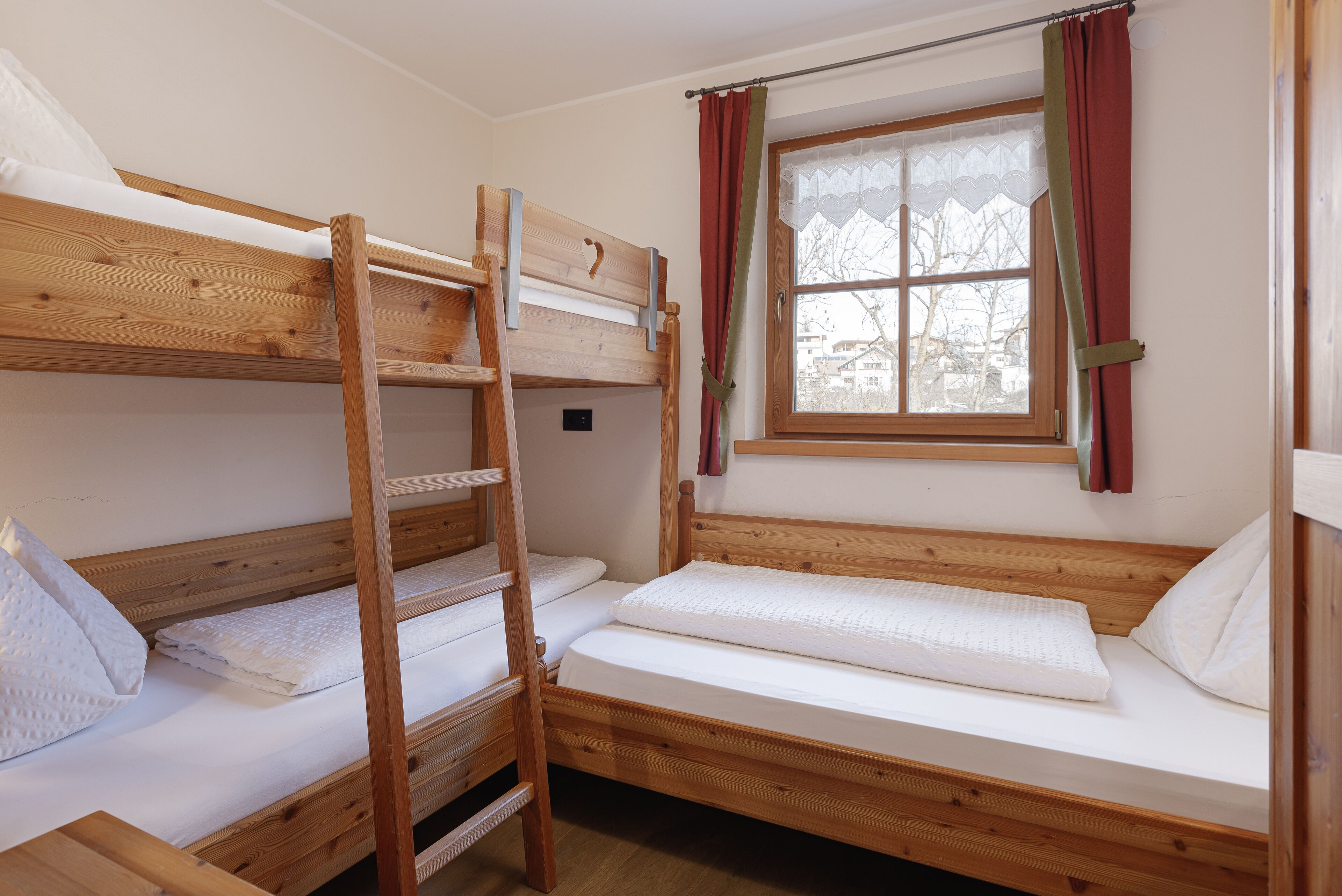 A bunk bed room with a window and curtains.