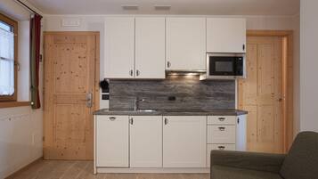 A compact kitchen with wooden cabinets, a built-in microwave, and a sink.