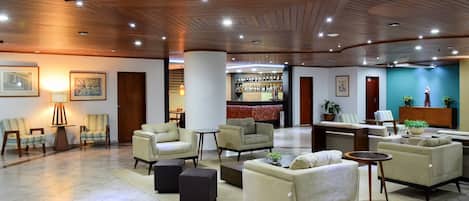 A spacious lobby with multiple seating areas, a bar, and a reception desk.