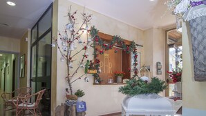 Un vestíbulo con piso a cuadros, sillas de madera, un árbol de Navidad y una vitrina de vidrio.