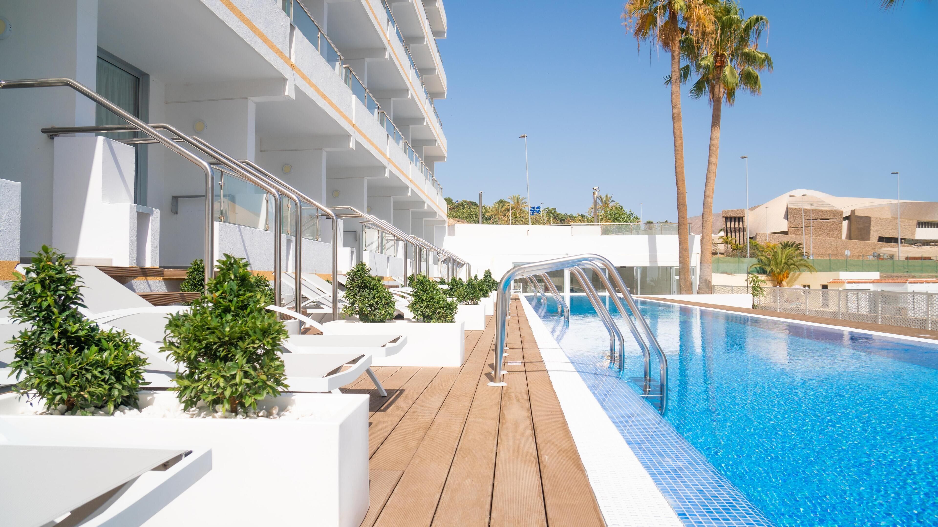 Alberca al aire libre, sombrillas en la alberca y camastros 