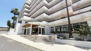 A modern multi-story building with a curved entrance and a staircase leading to the entrance.
