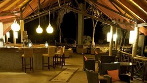 An outdoor seating area with wicker furniture, lanterns, and a wooden ceiling structure. - Ashnil Samburu Camp (Samburu)