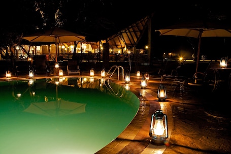 Una piscina al aire libre, sillones reclinables de piscina