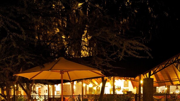 A nighttime pool area with lanterns and umbrellas. - Ashnil Samburu Camp (Samburu)