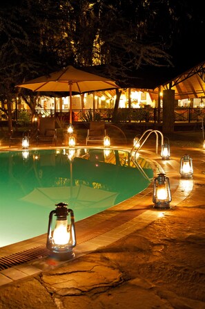 A nighttime pool area with lanterns and umbrellas. - Ashnil Samburu Camp (Samburu)