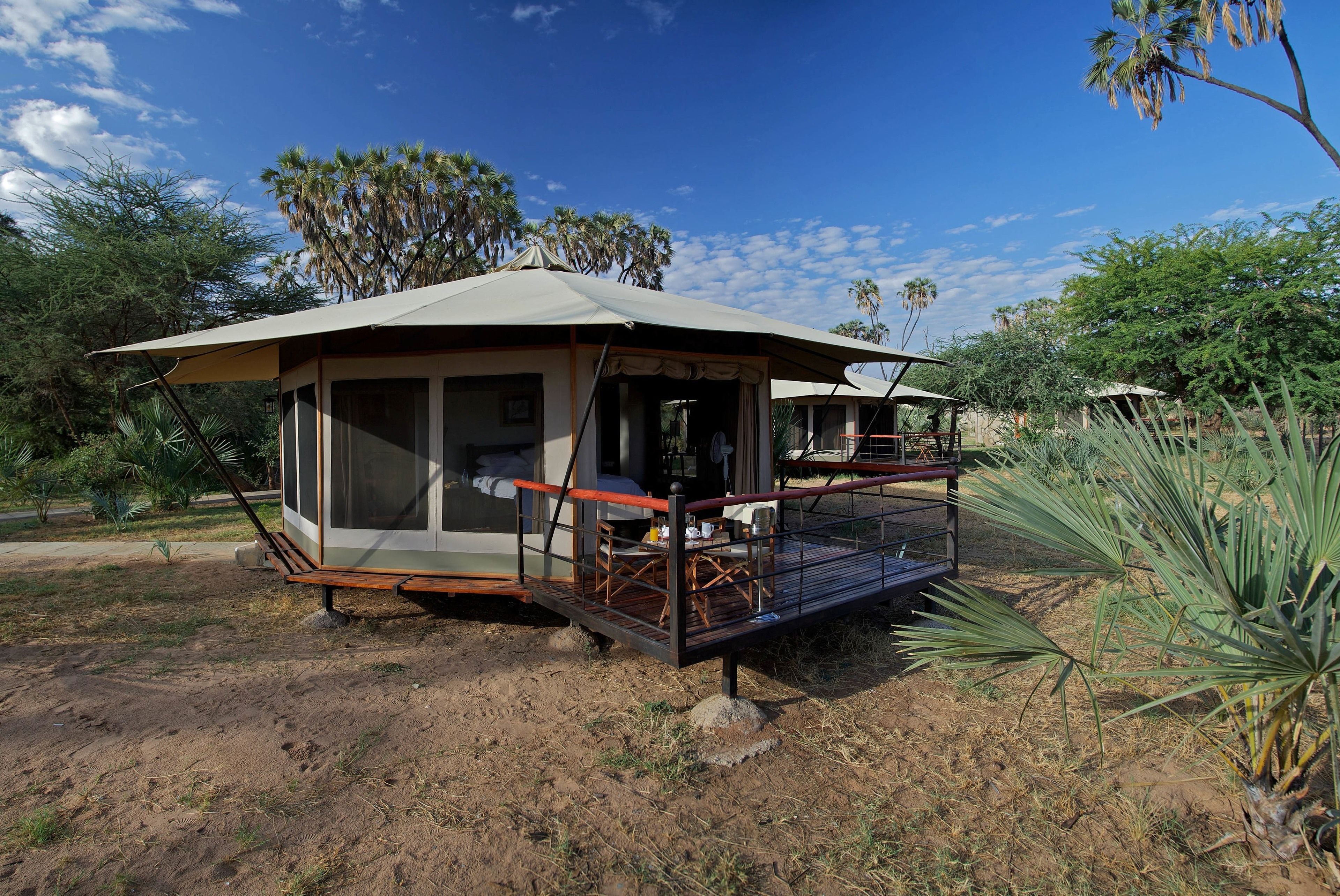 En safarilodge med en overdækket terrasse og en glasindhegning.
