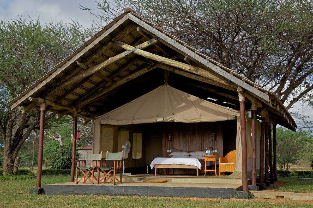 A rustic wooden structure with a covered porch, a bed, and seating area.