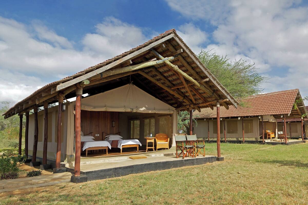 A rustic accommodation with a covered outdoor seating area, two bedrooms, and a dining area.