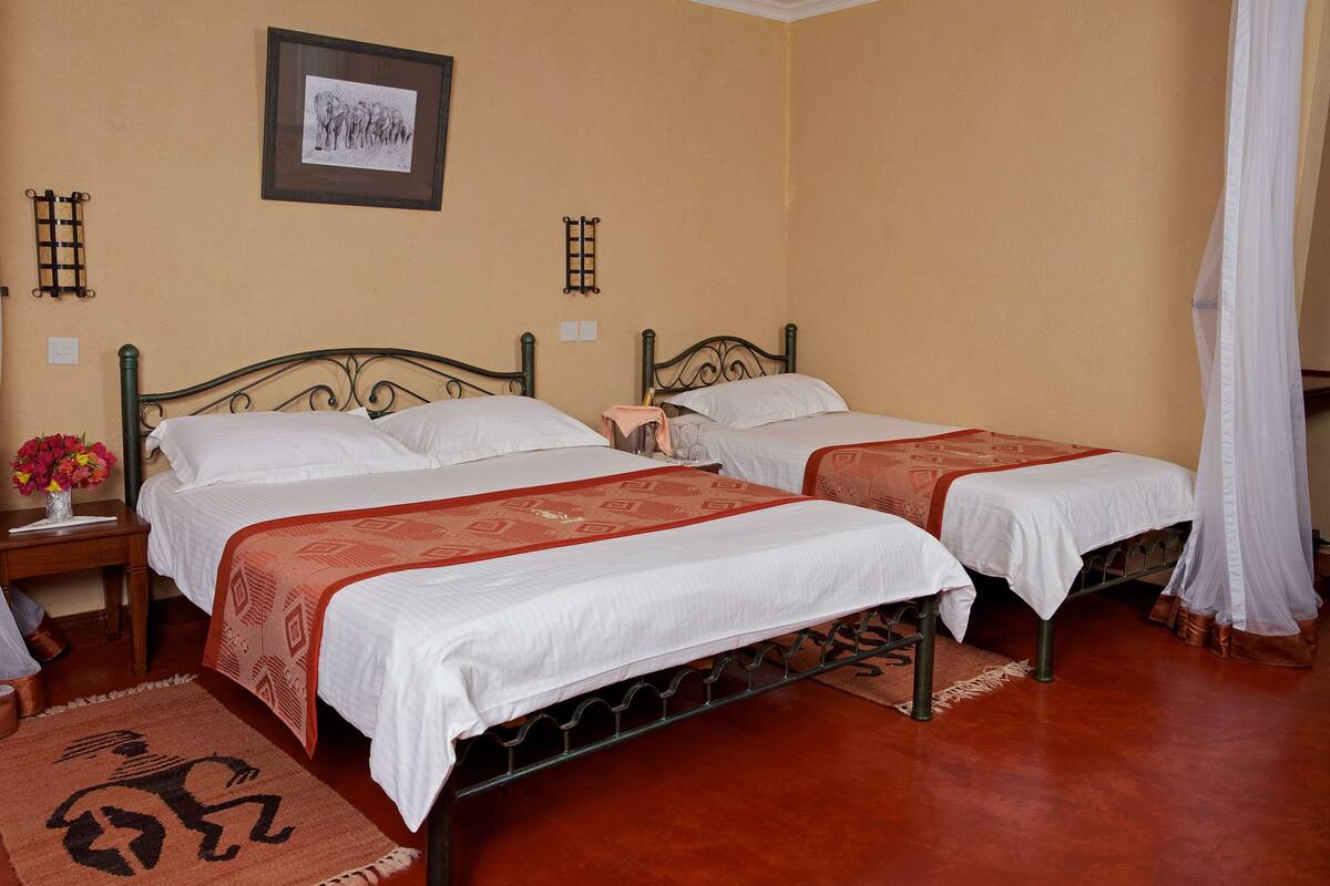 A hotel room with two beds, a nightstand, a framed picture, and a decorative rug.