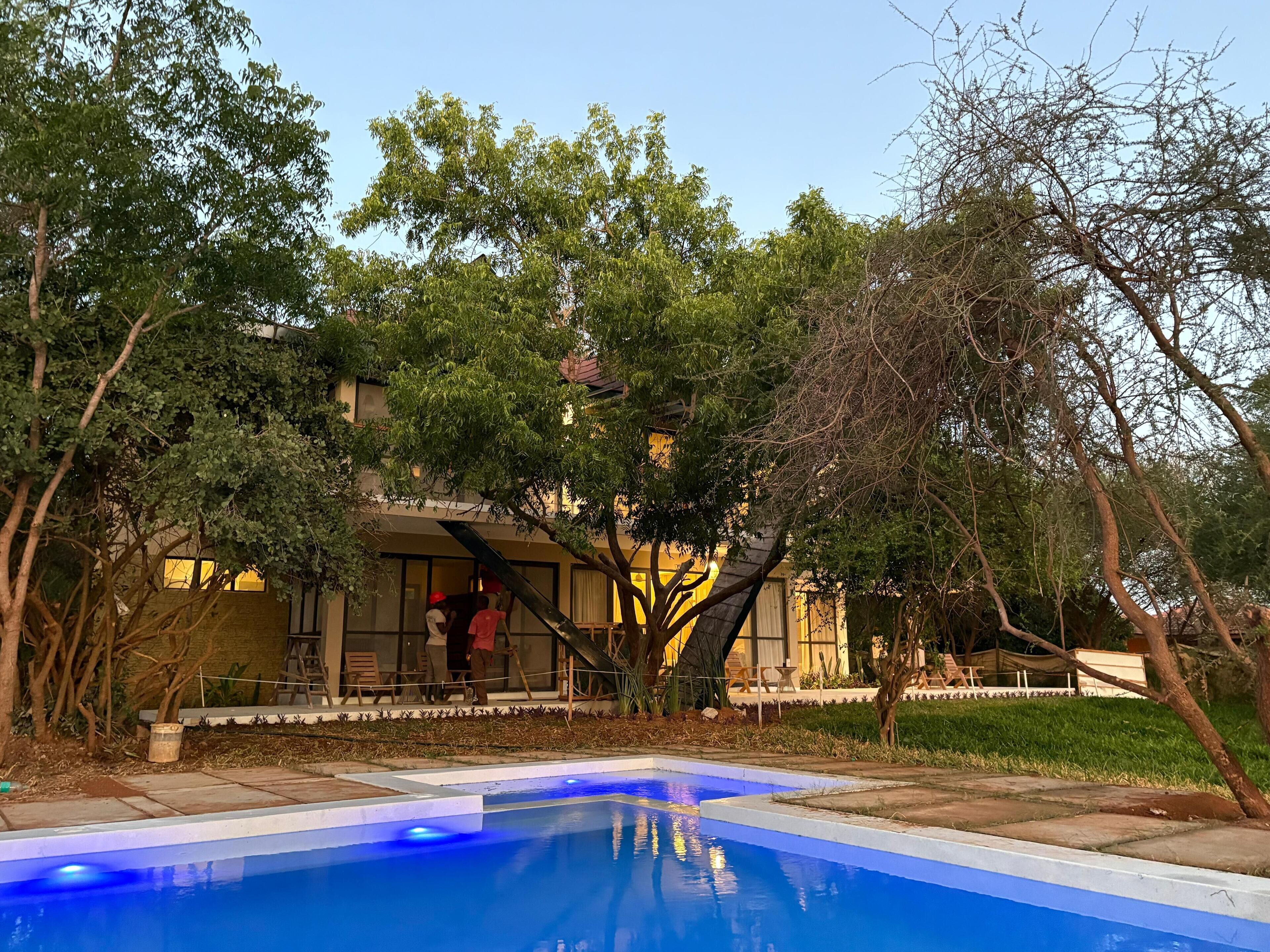 Una piscina rodeada de árboles y un edificio con un patio techado.