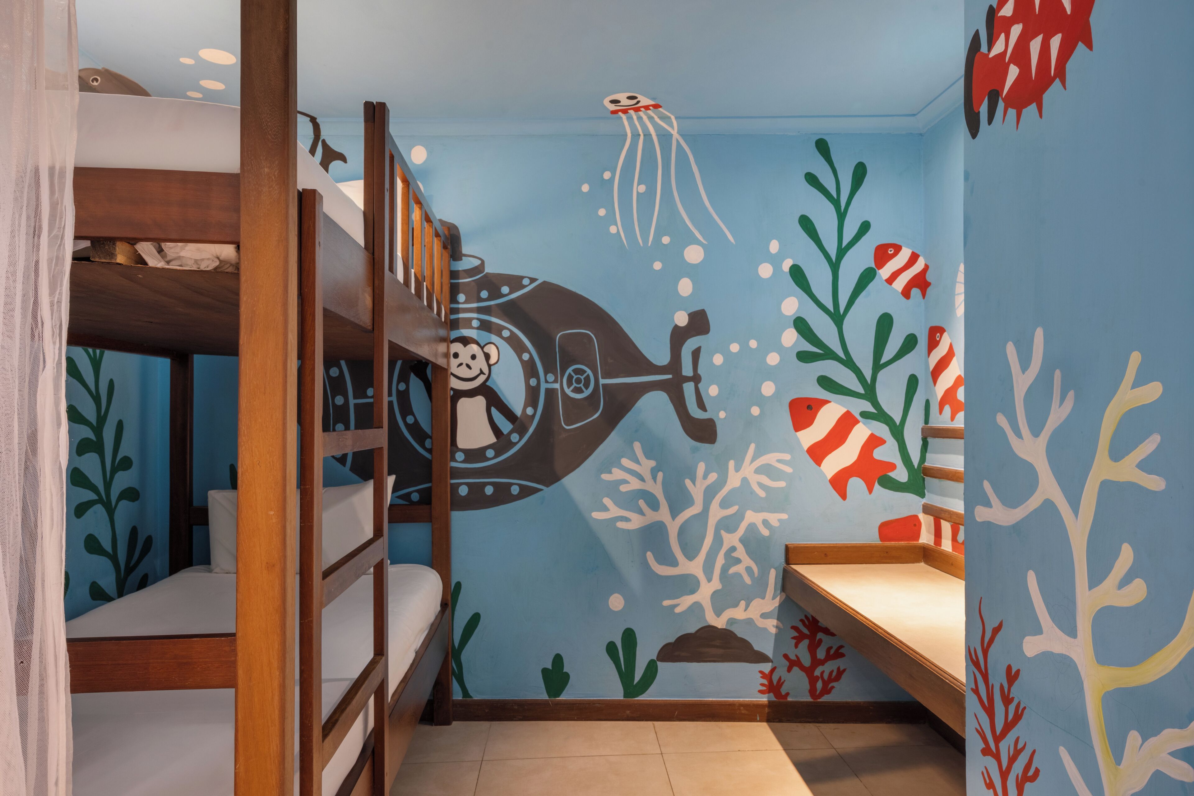 A bunk room with a blue wall decorated with marine life and a submarine.