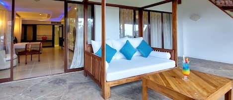 A room with a four-poster bed, a wooden coffee table, and a view of a dining area.