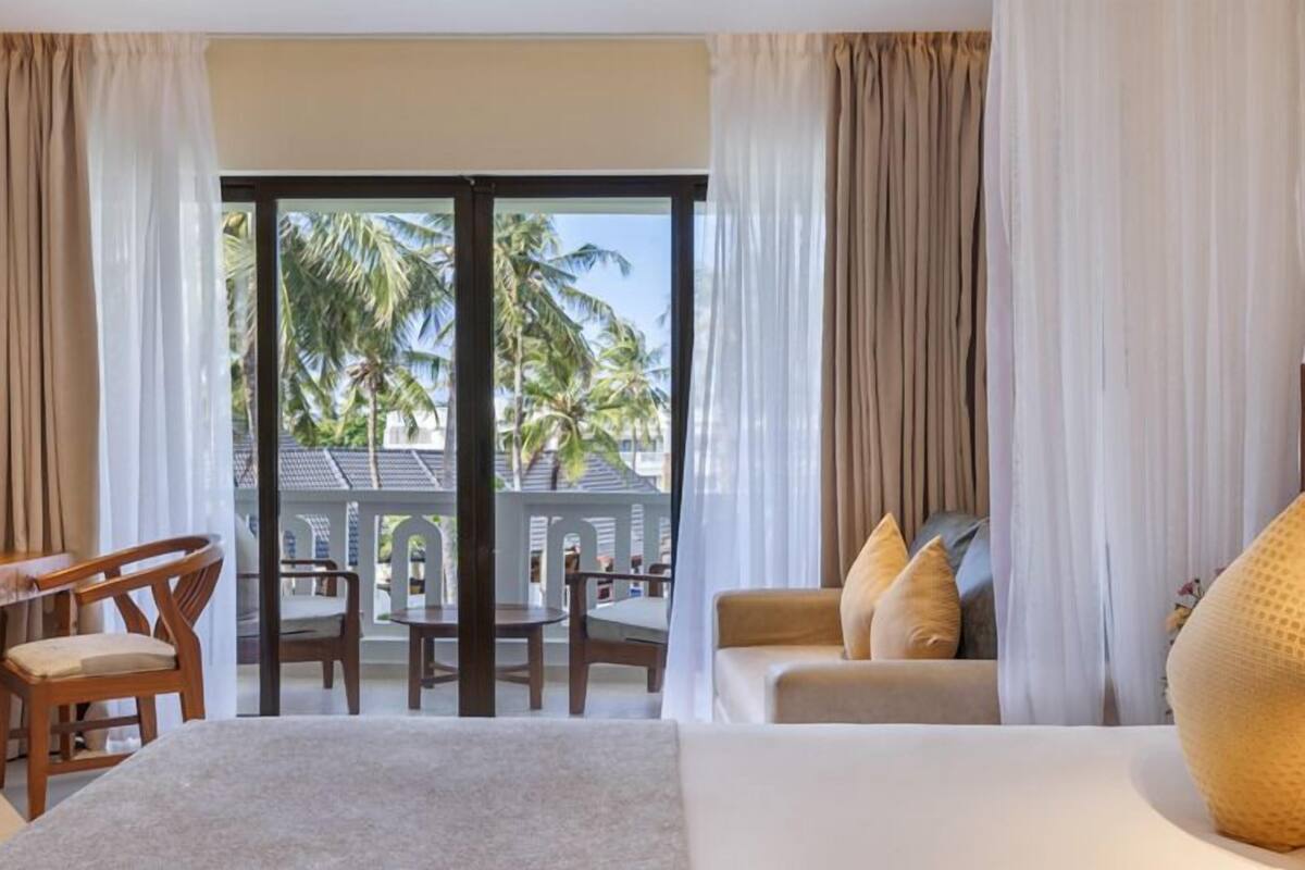 Una habitación de hotel con balcón, cama, escritorio y silla.