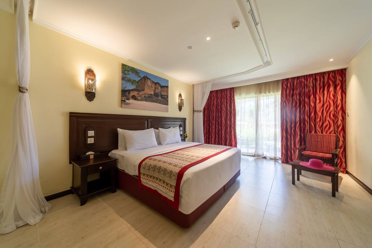 Una habitación de hotel con una cama grande, una mesita de noche, una silla y un cuadro en la pared.