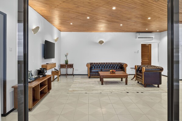 A modern living room with a flat-screen TV mounted on the wall, a wooden coffee table, a sofa, and a loveseat.