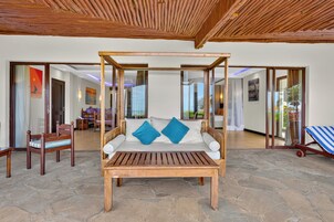 Una habitación con una cama de madera con dosel, suelo de piedra y vistas a través de puertas de cristal.