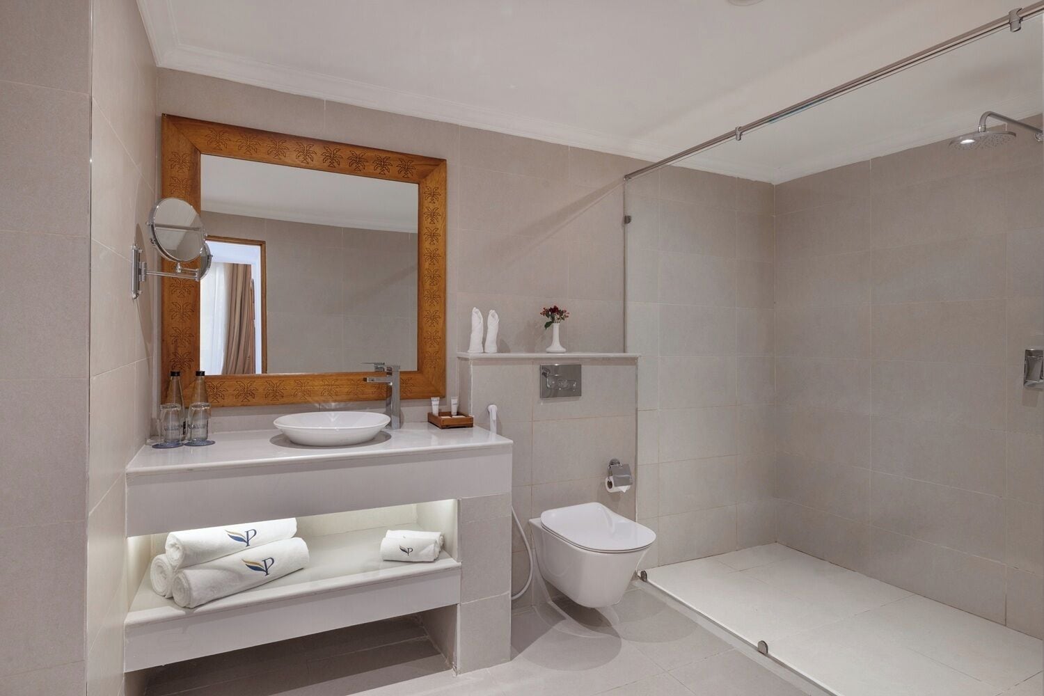 A modern bathroom with a vanity, sink, mirror, and shower area.