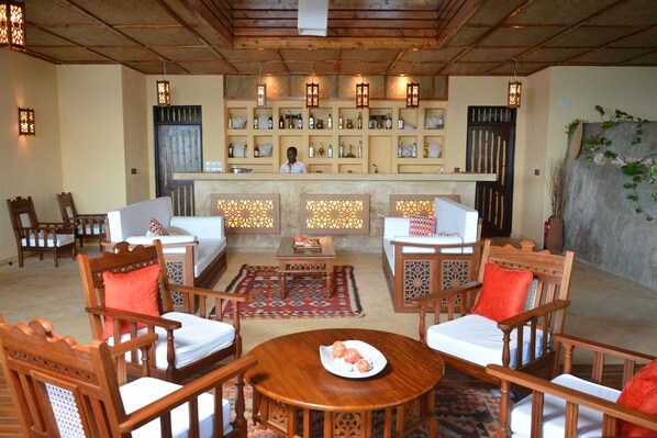A lobby with wooden furniture, a bar area, and a decorative wall with bottles.