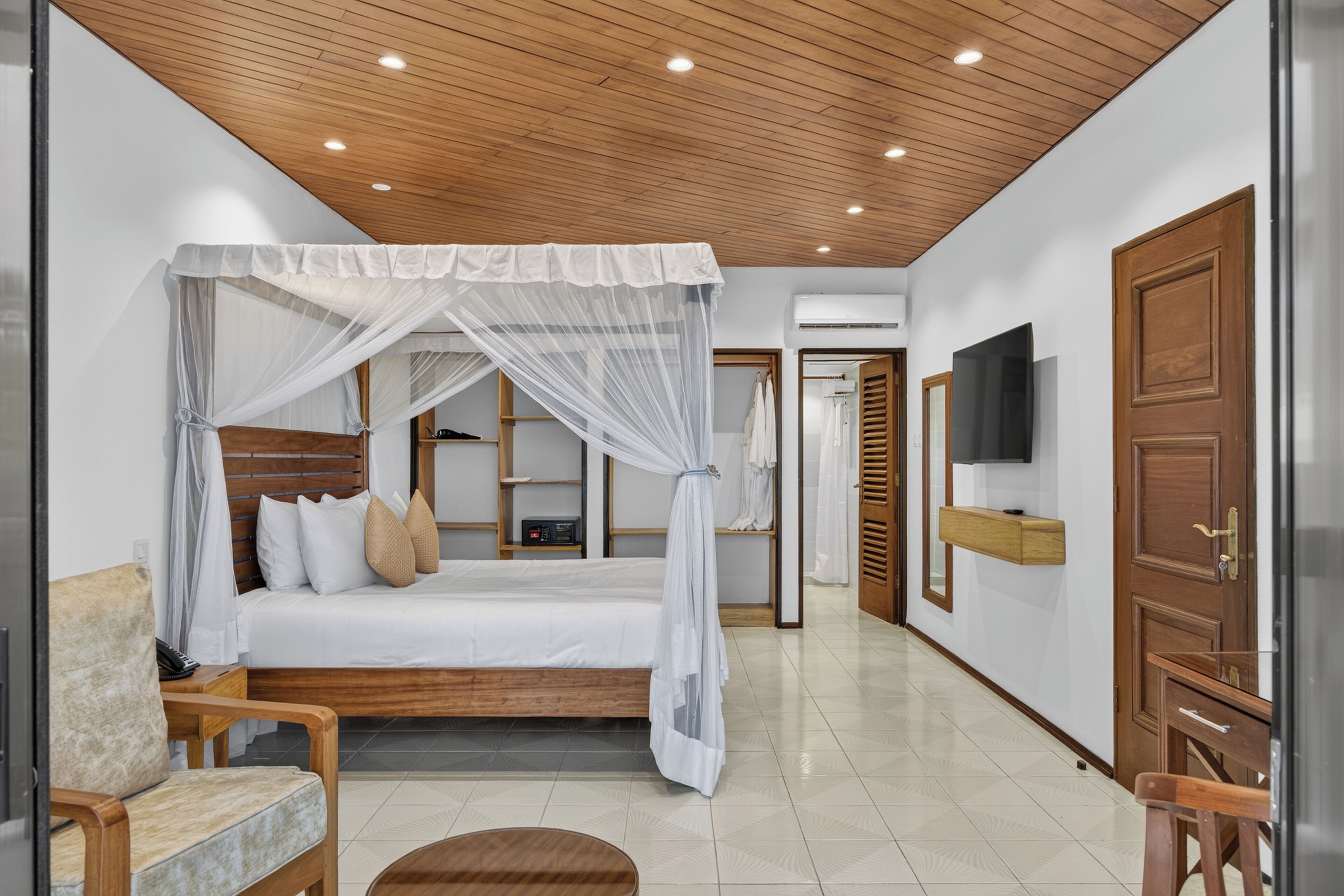 Une chambre à coucher moderne avec un lit à baldaquin, des meubles en bois et un téléviseur à écran plat fixé au mur.