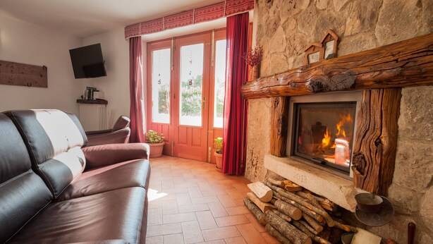 Una sala de estar acogedora con chimenea de piedra, sofá de cuero y televisión montada en la pared.