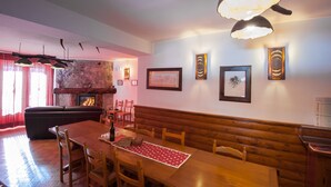 Un comedor con una mesa de madera, sillas, un banco y una chimenea.